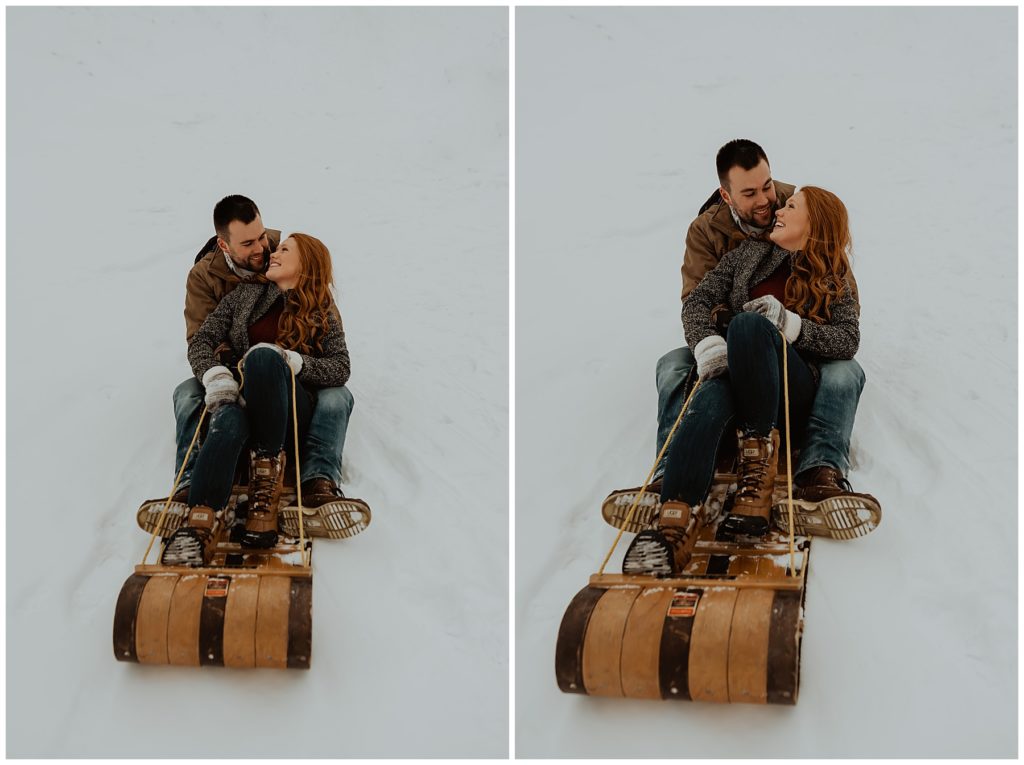 Couple sitting on sled after sledding down the dune at Lake Town Beach Holland, Michigan